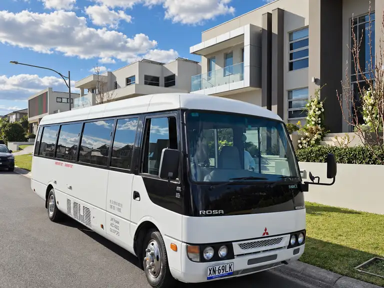 White Mitsubishi Rosa minibus on a street.