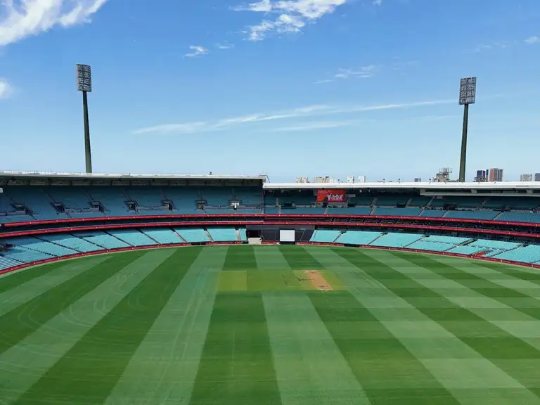 Sydney Cricket Ground with empty stands and striped grass under a clear sky