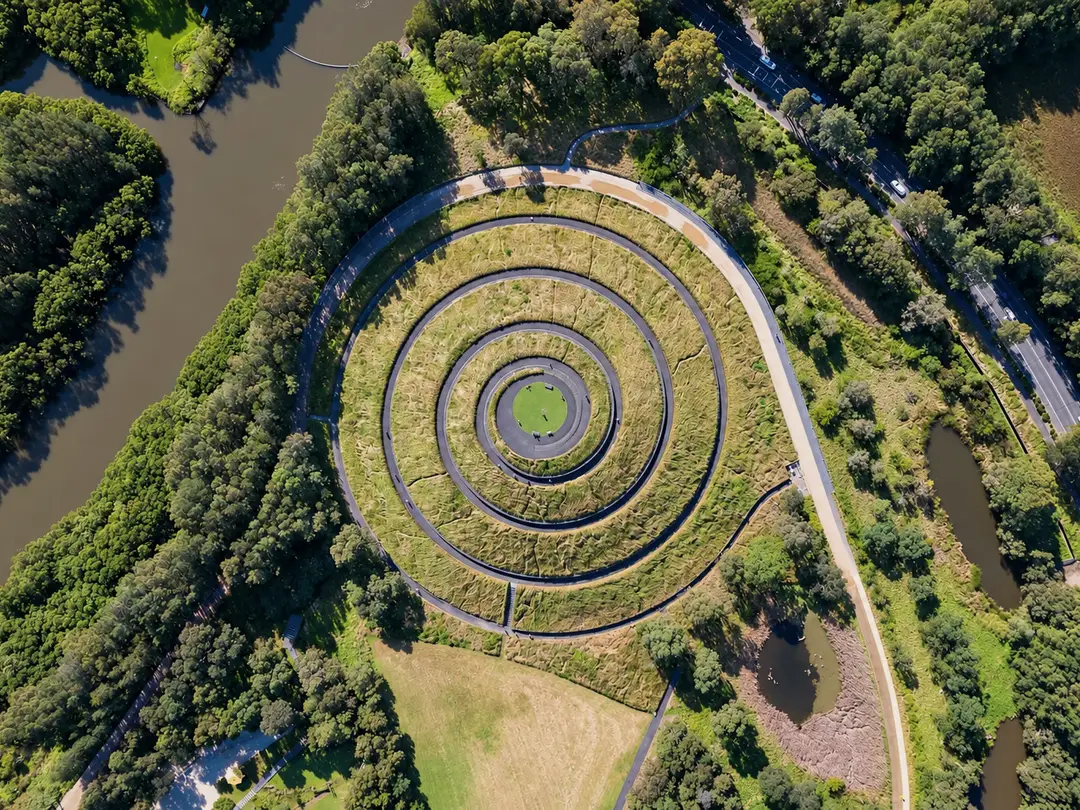 Aerial view of a spiral earthwork among trees at Sydney Olympic Park, NSW.